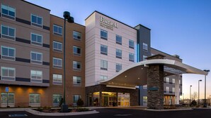 Un hotel de varios pisos con diseño moderno, que cuenta con una entrada destacada con un vestíbulo cubierto y un letrero que dice "Fairfield by Marriott".
