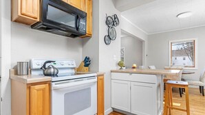 A modern kitchen with white cabinets, a stainless steel microwave, a gas stove, and wooden countertops. - Stylish, Spacious Home: Walk Downtown, Fenced Yard on Washington St. (Appleton)