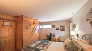 Een gezellige slaapkamer met een groot bed, een houten garderobe, een stoel en een bureau met een lamp.