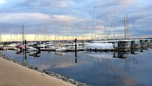 A marina with boats docked, calm water, and a cloudy sky.
