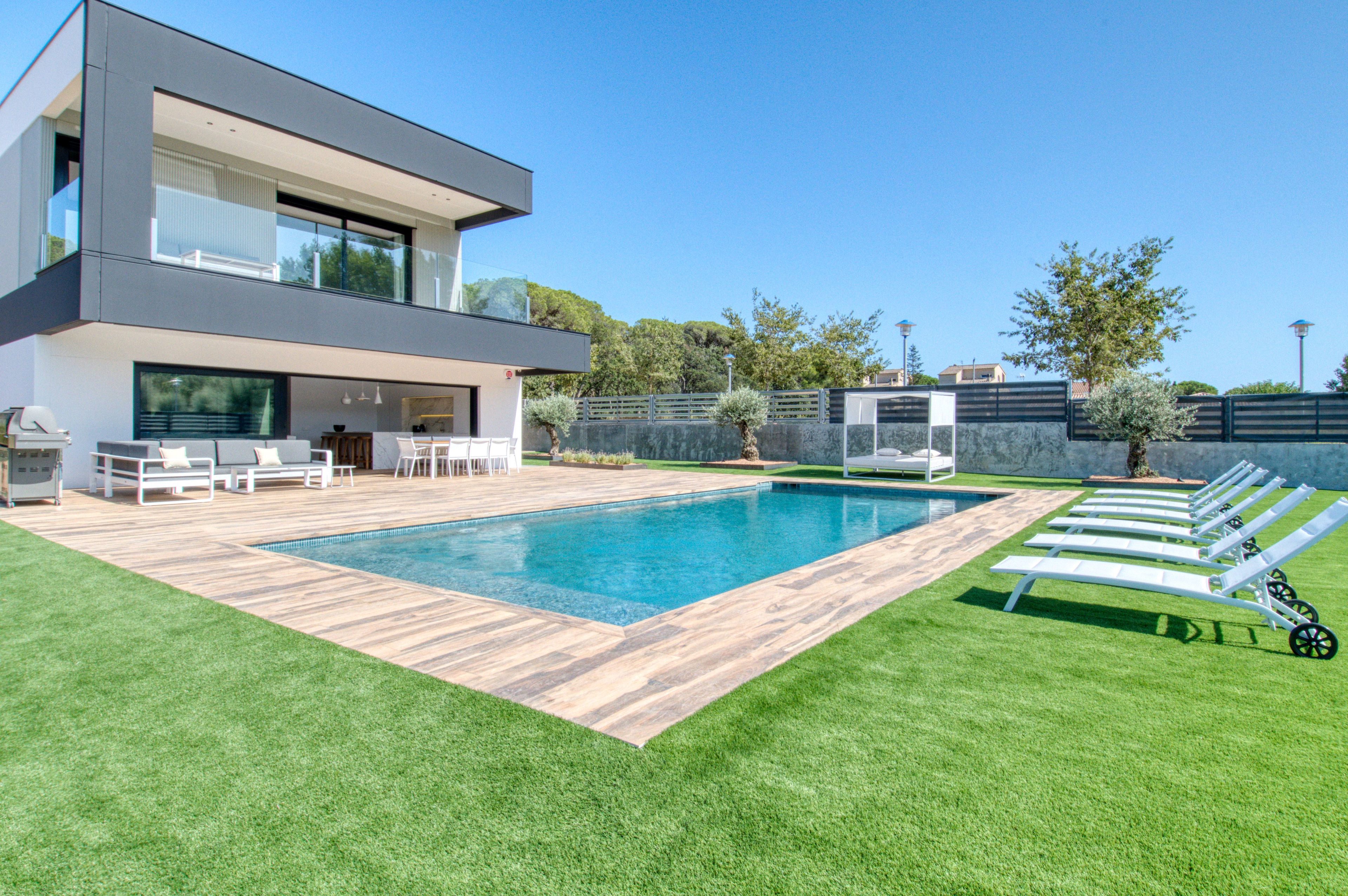 Een modern huis met een zwembad, terras en een verzorgd gazon.