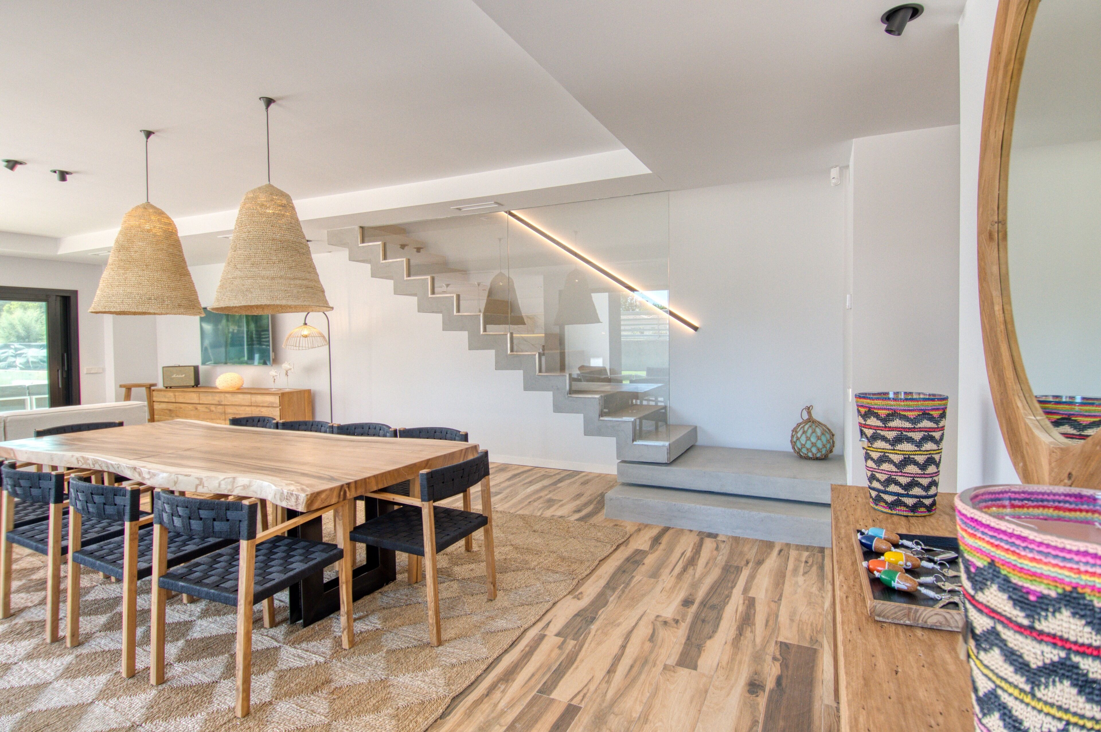 Ein moderner Essbereich mit einem Holztisch, Stühlen, einer Treppe und einem großen Spiegel.