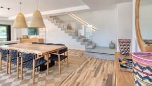 Un espace repas moderne avec une table et des chaises en bois, un escalier et un grand miroir.