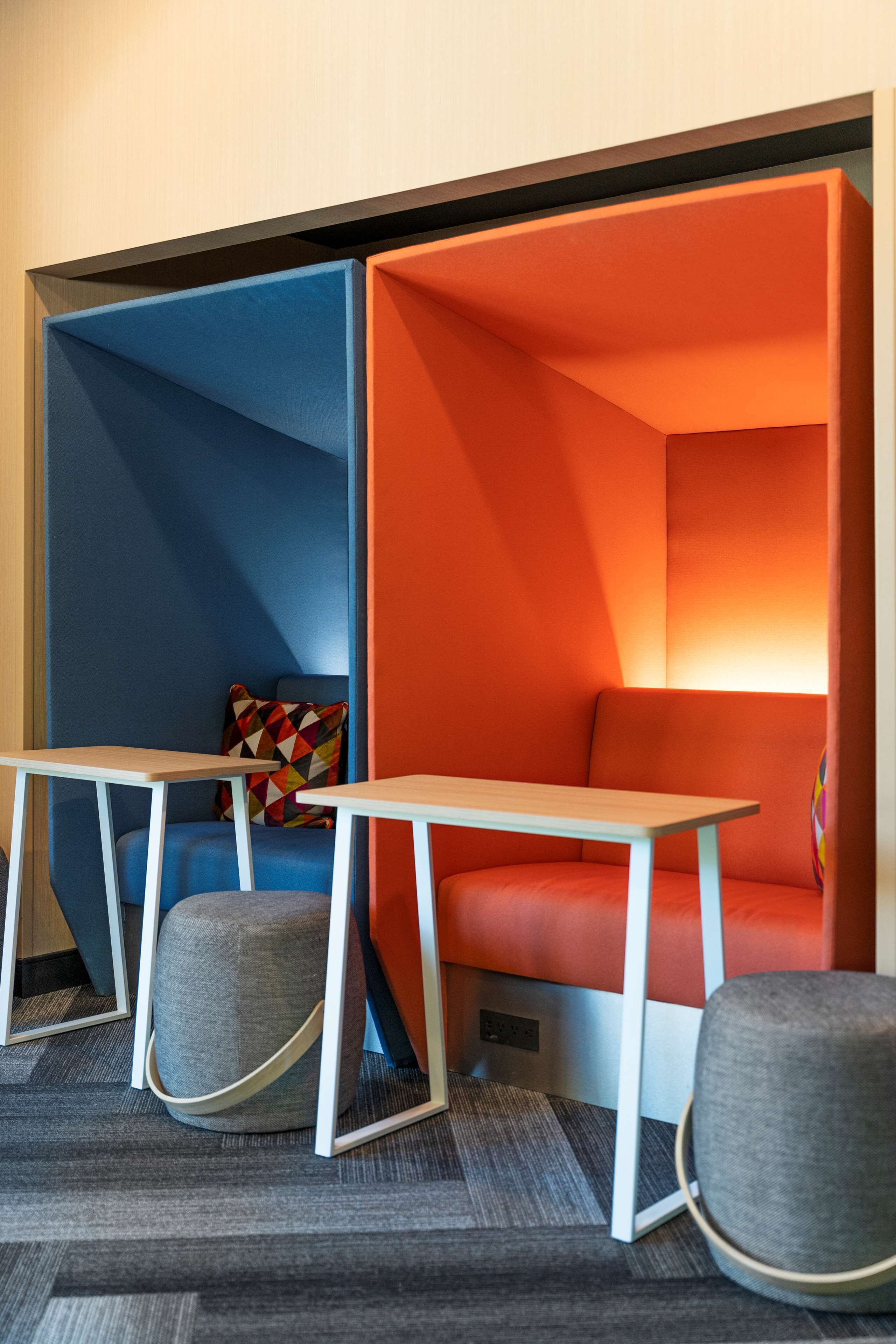 A room with a blue and orange partition, a small table, and a grey ottoman.