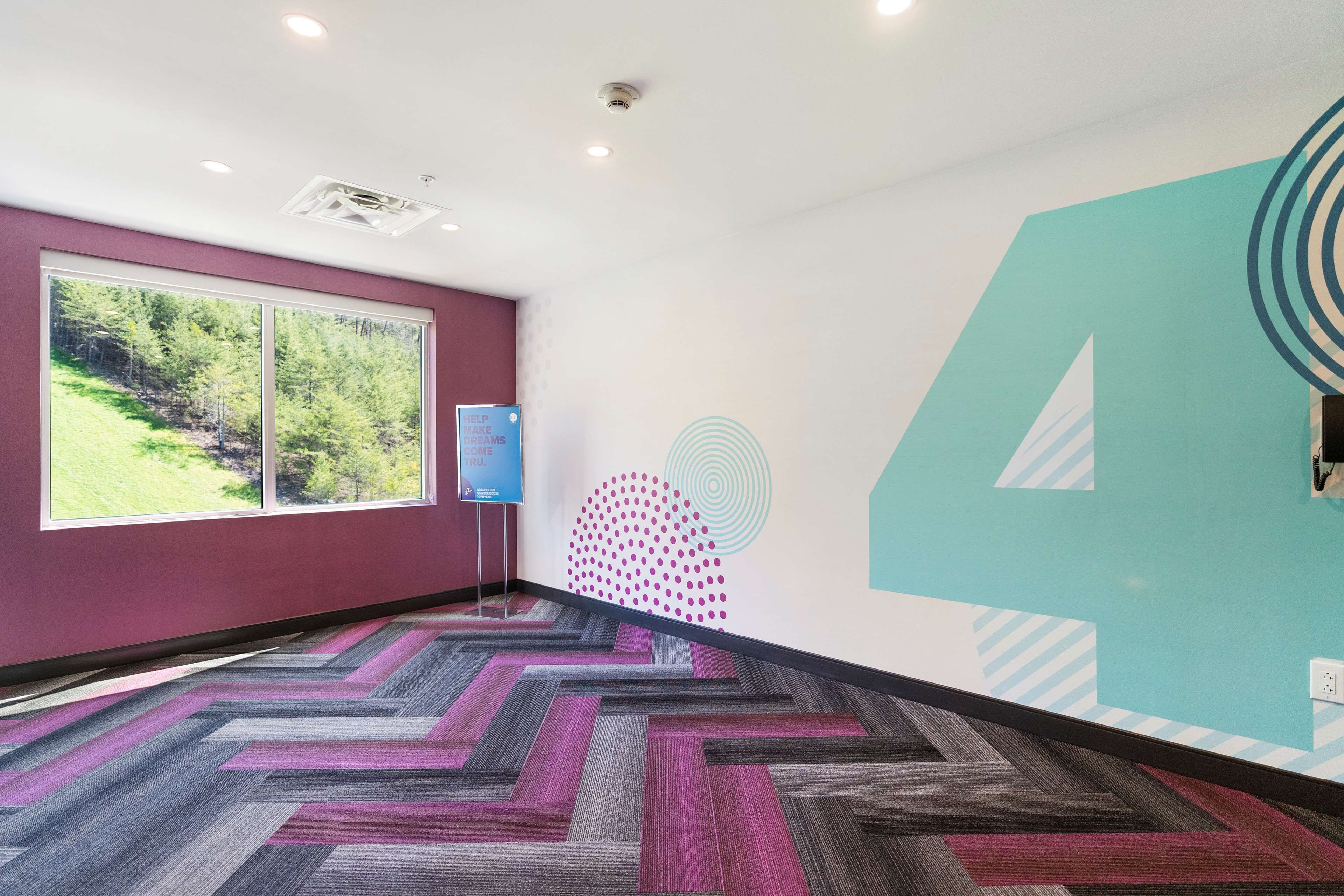 Un interior moderno con un ventanal grande, una alfombra estampada y un muro con diseño geométrico.