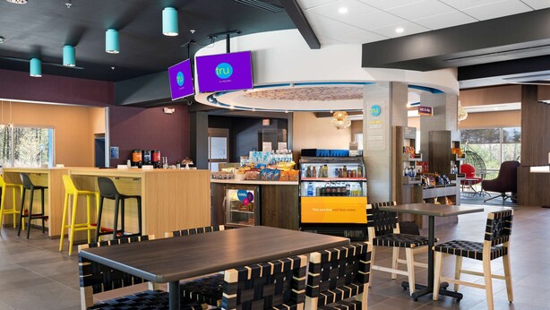 Un intérieur de restaurant moderne avec un bar, des tables et des chaises, et un comptoir où sont présentés divers plats.