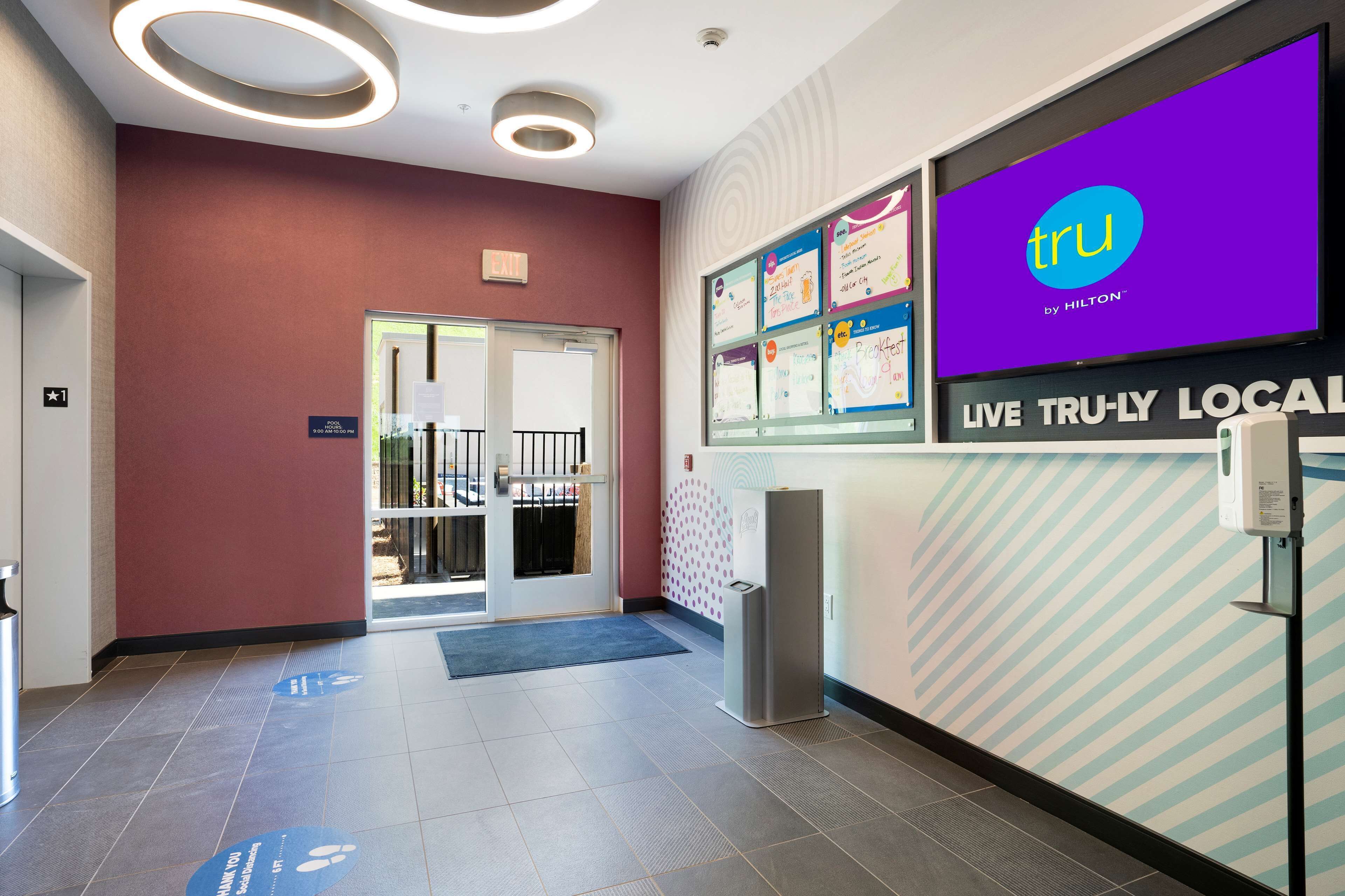 A hotel reception area with a modern design, including a large screen displaying the hotel's name and a sign for the reception desk.