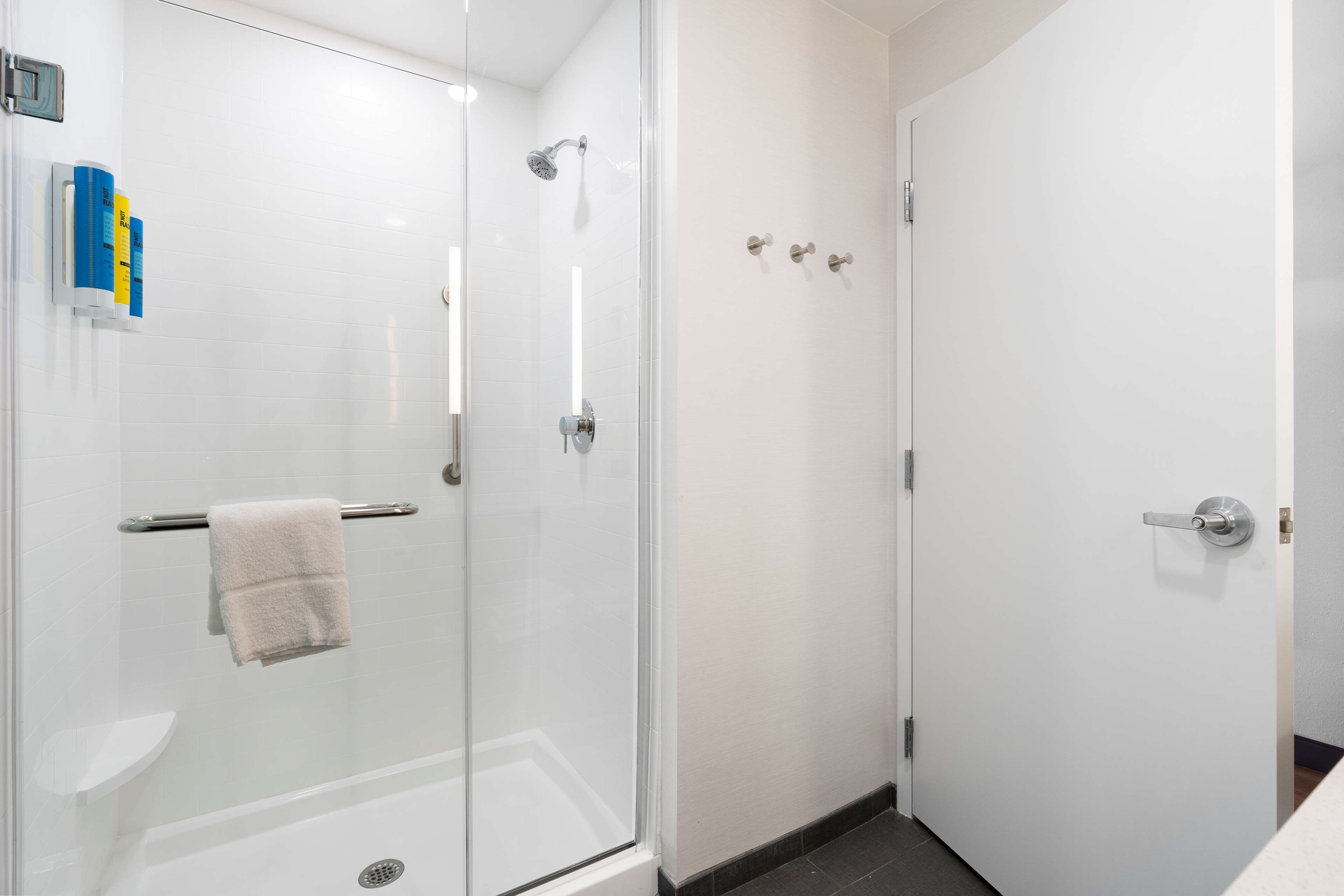 Een moderne badkamer met een douchecabine van glas, een wit toilet en een witte deur.