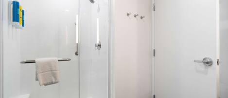 Een moderne badkamer met een douchecabine van glas, een wit toilet en een witte deur.