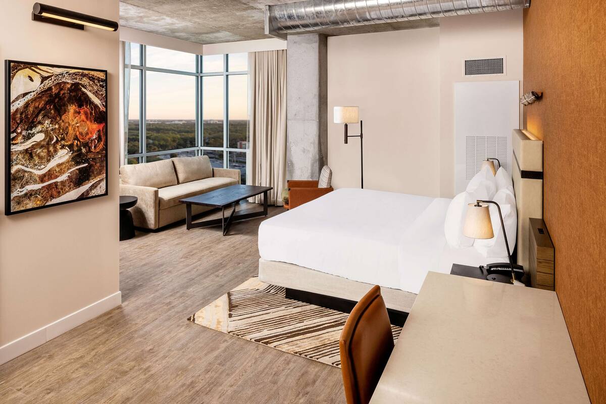 Une chambre d’hôtel avec un grand lit, un canapé, un bureau et une vue sur la ville.