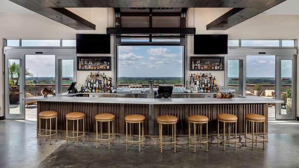 Eine Bar mit hoher Decke, großen Fenstern und Landschaftsblick.
