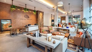 Eine moderne Hotelhalle mit Rezeption, Sitzgelegenheiten und großen Fenstern.