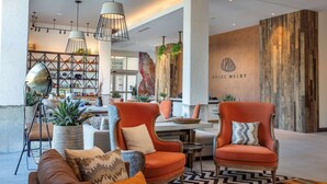 Eine moderne Lobby mit einer Rezeption, zwei roten Sesseln, einem Sofa und einem gemusterten Teppich.