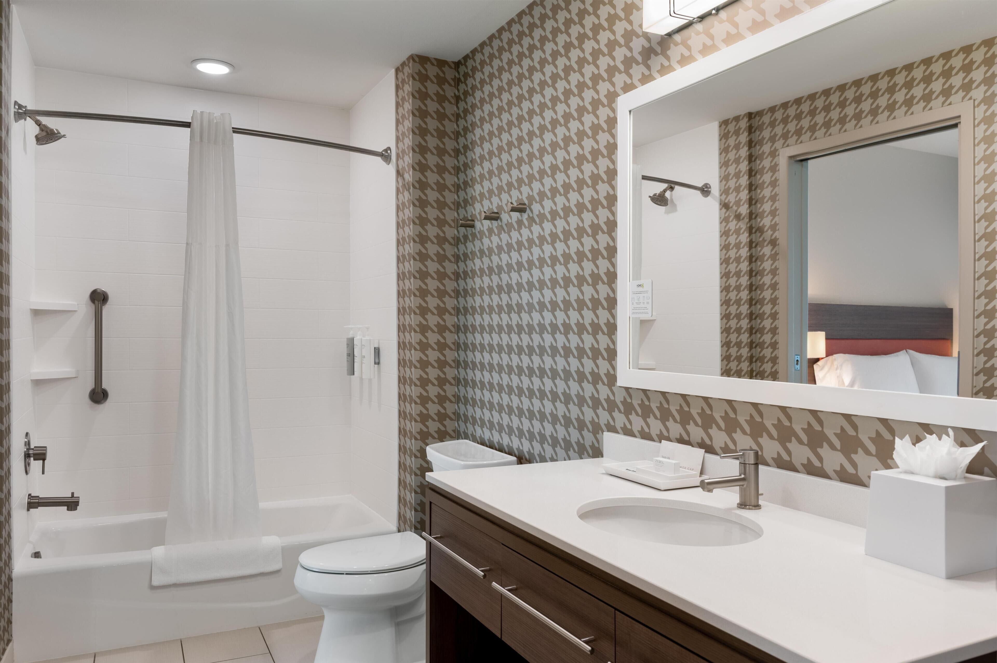 A modern bathroom with a bathtub, toilet, and vanity with a mirror.
