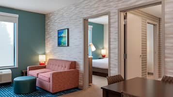 A hotel room with a sofa, a small table, a lamp, and a bed.