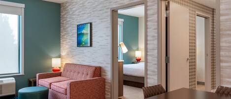 A hotel room with a sofa, a small table, a lamp, and a bed.