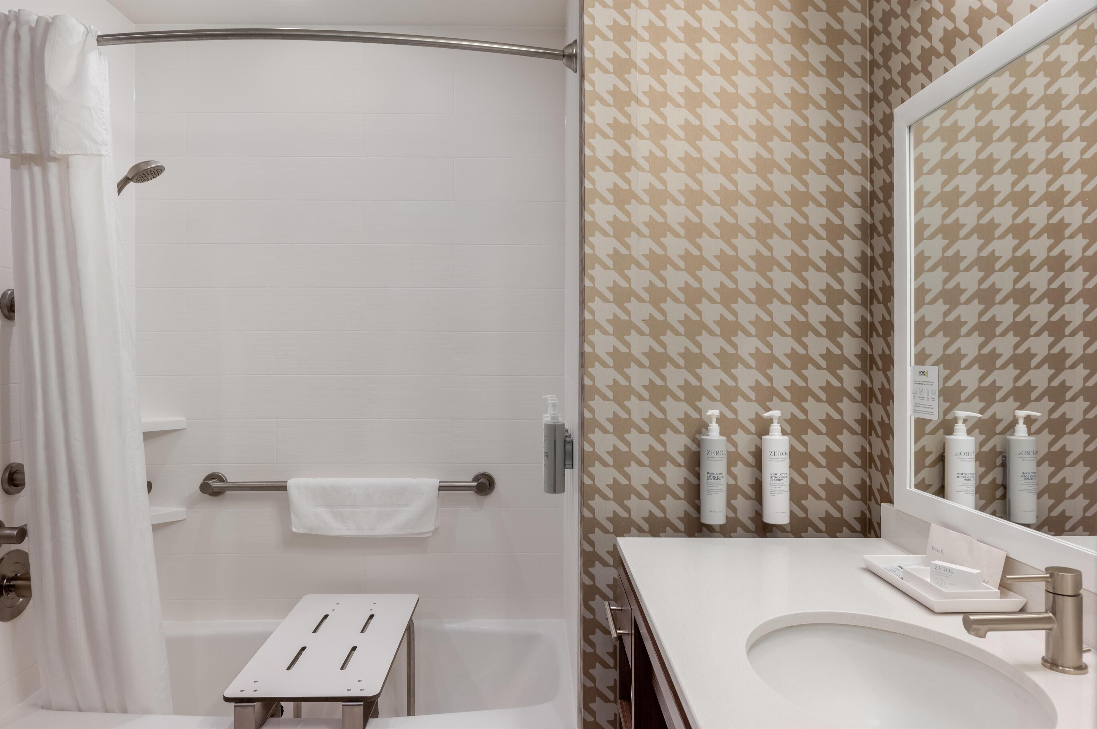 A bathroom with a shower, a sink, and toiletries.