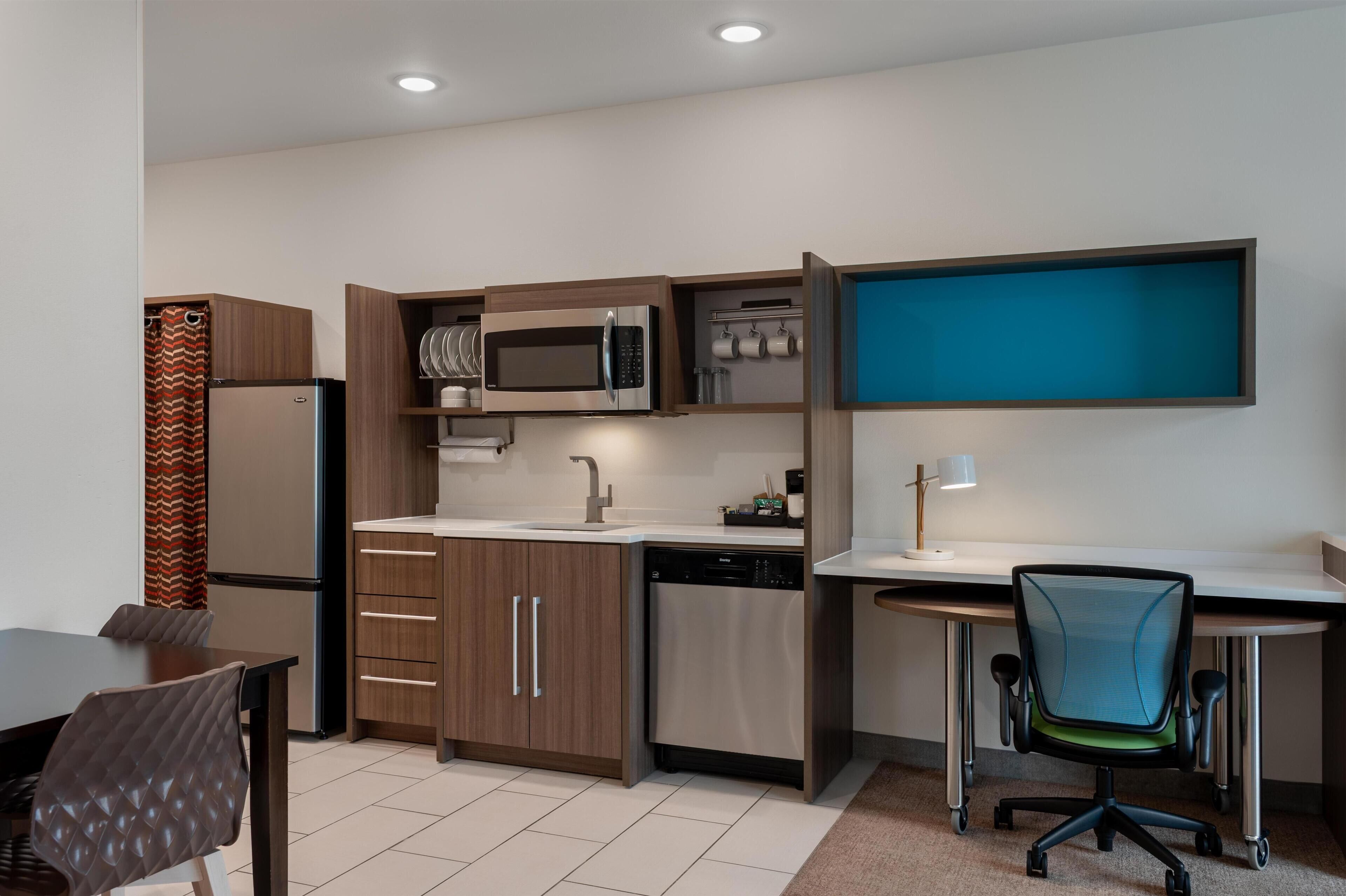 A compact kitchen with a microwave, dishwasher, and a small dining area with a table and chairs.