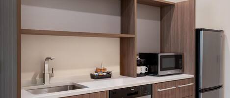 A modern kitchen with a stainless steel refrigerator, a built-in microwave, a coffee maker, and a dishwasher.