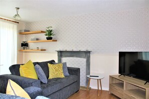 Relax in this stylish living room with a sofa, flat-screen TV, and fireplace.