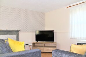 Relax in this stylish living room with a flat-screen TV, geometric-patterned wall, and comfortable seating for two.