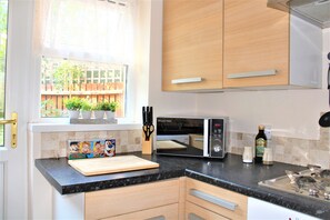 Enjoy cooking in this well-equipped kitchen with a microwave, countertop for food preparation, and a window offering a view of the surrounding greenery.