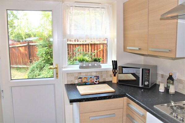 Enjoy a kitchen with a window overlooking the backyard, microwave, toaster, and cutting board on the countertop.