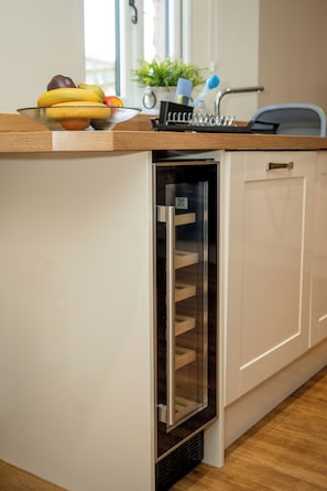 Une cuisine équipée d’appareils électroménagers intégrés, avec un panier de fruits sur le plan de travail et un évier.