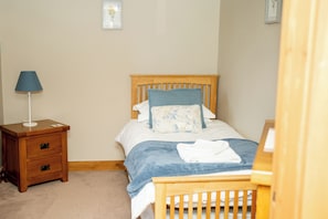 Une chambre à coucher avec un lit en bois, une table de chevet avec une lampe et une commode.
