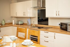 Une cuisine moderne avec des meubles blancs, un plan de travail en bois, un four encastré et un four à micro-ondes.
