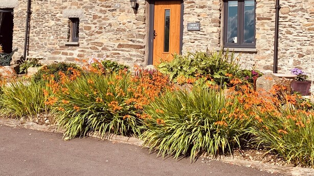 A stone building with a wooden door, windows, and a sign indicating it is a cottage. - Stunning 3 bed cottage with exceptional views over fields and the Lakeland fells (Kendal)