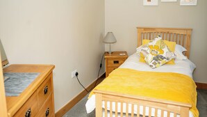 A bedroom with a wooden bed, a nightstand, a lamp, and a dresser. - Stunning 3 bed cottage with exceptional views over fields and the Lakeland fells (Kendal)