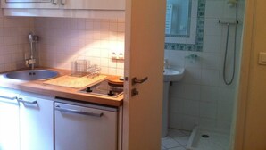 A compact kitchen with a microwave, sink, and dish rack.
