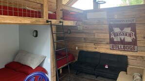 Habitación tipo dormitorio con literas, una escalera, un aro de baloncesto y un banderín de los Bulldogs de Mississippi State.