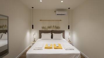 Hotelkamer met een groot bed, twee nachtkastjes, een wandairconditioner en een spiegel aan de linker muur.