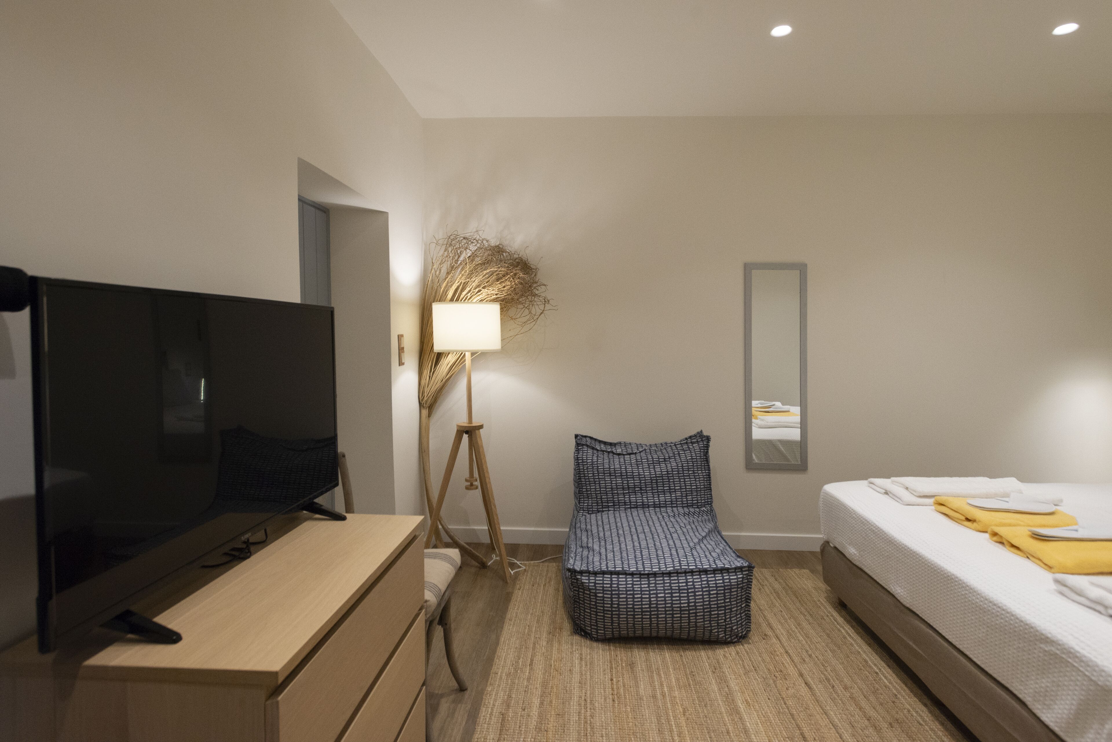 Een moderne hotelkamer met een flatscreen-tv, een nachtkastje, een lamp, een bank en een bed met netjes opgemaakte handdoeken.