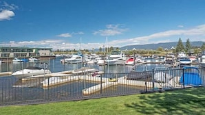 A marina with boats docked, a building with a green roof, and a clear blue sky.