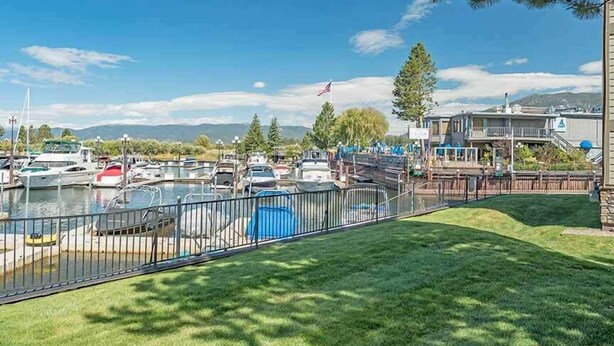 A marina with boats docked, a grassy area, and a building with a flag.