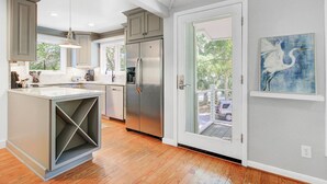 A modern kitchen with a central island, stainless steel appliances, and a sliding glass door leading to an outdoor area.