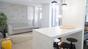 A modern kitchen with a white countertop, black stools, and pendant lighting. - FLH Alfama Traditional Flat (Lisbon)