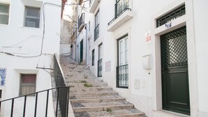 A narrow staircase leading to a building with a green door and a window with a metal grill. - FLH Alfama Traditional Flat (Lisbon)
