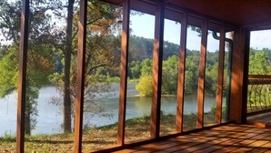 Una terraza de madera con vista a un lago rodeado de árboles.