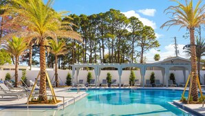 A swimming pool with lounge chairs and palm trees. - Golf Cart ~ Screened Patio ~ Golf Course Views (Miramar Beach)