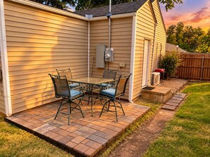 Une terrasse avec une table et des chaises, un espace abrité et une clôture en bois en arrière-plan.