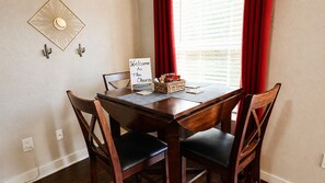 Une table à manger avec une enseigne, des chaises et une fenêtre avec des rideaux.