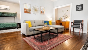 A living room with a sofa, coffee table, and a red patterned rug. - The Charm | Dog Friendly | Downtown | Fiber WiFi (Chickasha)