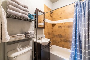 A bathroom with a wooden shower wall, a white sink, and a bathtub.