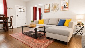Un salon comprenant un canapé, une table basse et un coin repas avec des chaises.