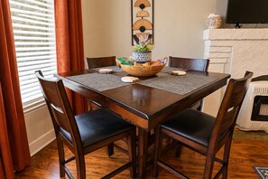 Un'area pranzo con un tavolo in legno, quattro sedie, una ciotola decorativa e un camino.