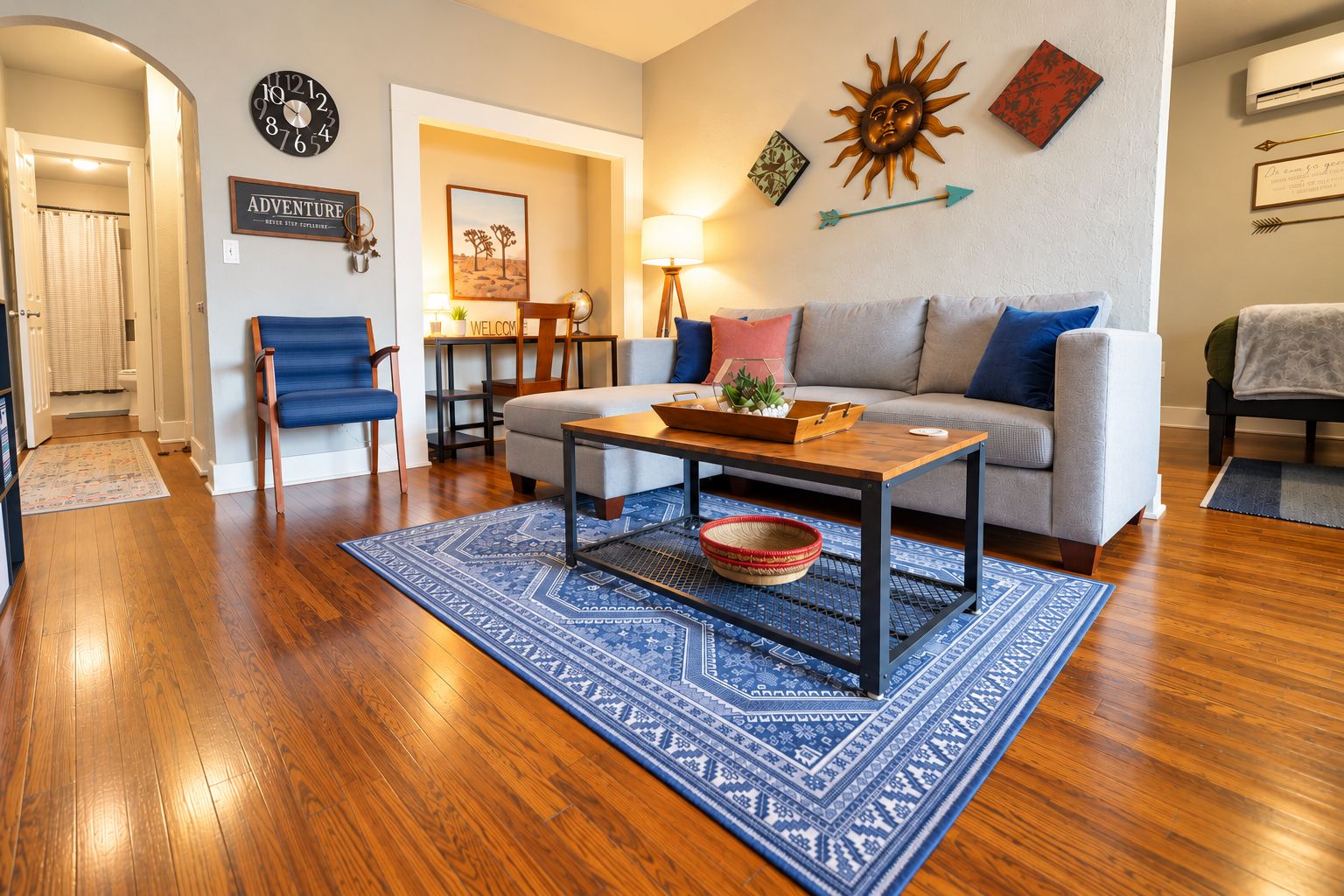 Un salon avec un canapé, une table basse et un tapis bleu à motifs.